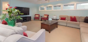 A living room with a flat-screen TV, a coffee table, and seating including a sofa and two armchairs.