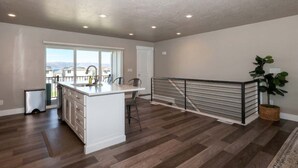 Een moderne keuken met een centraal eiland, een eetgedeelte en een balkon met uitzicht.
