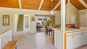 A spacious kitchen with wooden cabinets, a dining area with chairs, and a staircase leading to another level. - Hale Kai Kea | 3 King Suites, Bonus Room, Lanai & Tropical Paradise (Koloa)