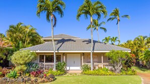 A two-story house with a tiled roof, surrounded by tropical vegetation and palm trees. - Hale Kai Kea | 3 King Suites, Bonus Room, Lanai & Tropical Paradise (Koloa)