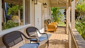 A covered outdoor seating area with wicker furniture and a view of the garden. - Hale Kai Kea | 3 King Suites, Bonus Room, Lanai & Tropical Paradise (Koloa)