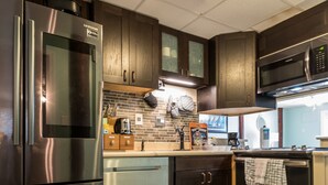 A modern kitchen with stainless steel appliances, dark wooden cabinets, and a tiled floor. - Discounts Summer Very Short Walk to Beach - 2BD/2BA Sleeps 6 (Miramar Beach)