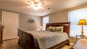 A bedroom with a wooden bed, a ceiling fan, a nightstand with a lamp, and a window with blinds. - Discounts Summer Very Short Walk to Beach - 2BD/2BA Sleeps 6 (Miramar Beach)