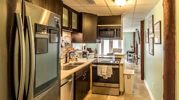 A modern kitchen with stainless steel appliances, dark wooden cabinets, and a central island.