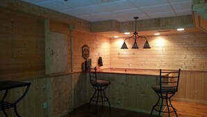 Eine Bar mit Holzwänden, einer Theke und drei Hockern.