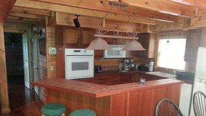 Eine kompakte Küche mit Holzausstattung, Backofen, Mikrowelle und einer Bar mit Sitzgelegenheiten.