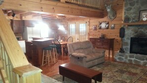 Ein gemütliches Blockhauss-Interieur mit Essbereich, Kamin und einer Treppe.