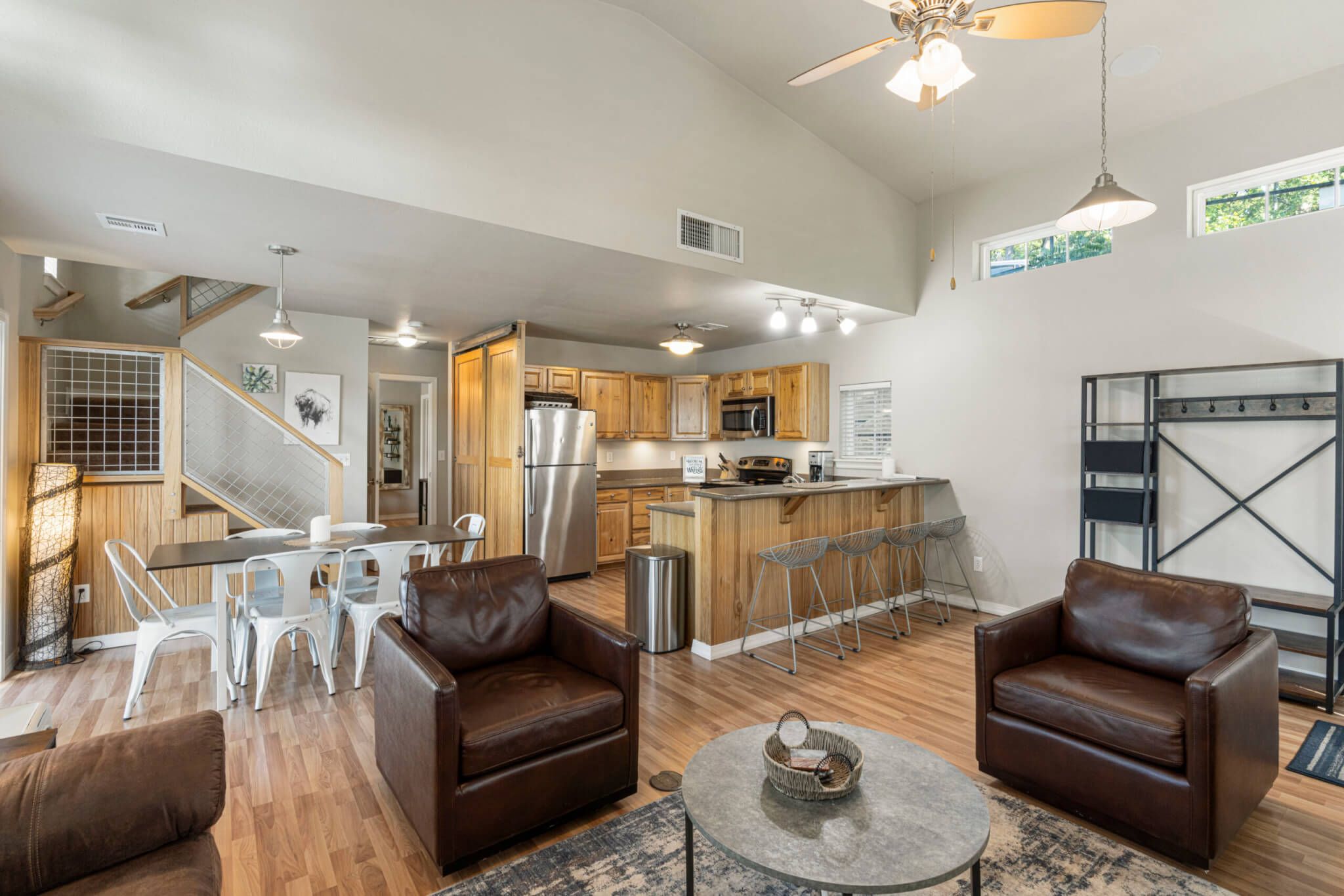 A modern kitchen with stainless steel appliances, a bar area, and a dining space with white chairs.