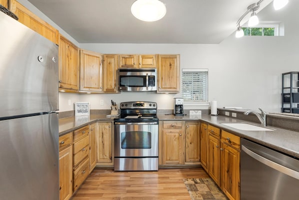 A modern kitchen with wooden cabinets, stainless steel appliances, and a built-in oven. - Hideaway at CrossTimbers Marina (Sperry)