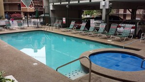 A pool area with lounge chairs and a hot tub.