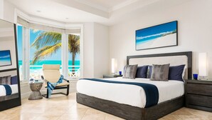 A modern hotel room with a large bed, a chair by the window, and a view of the ocean.