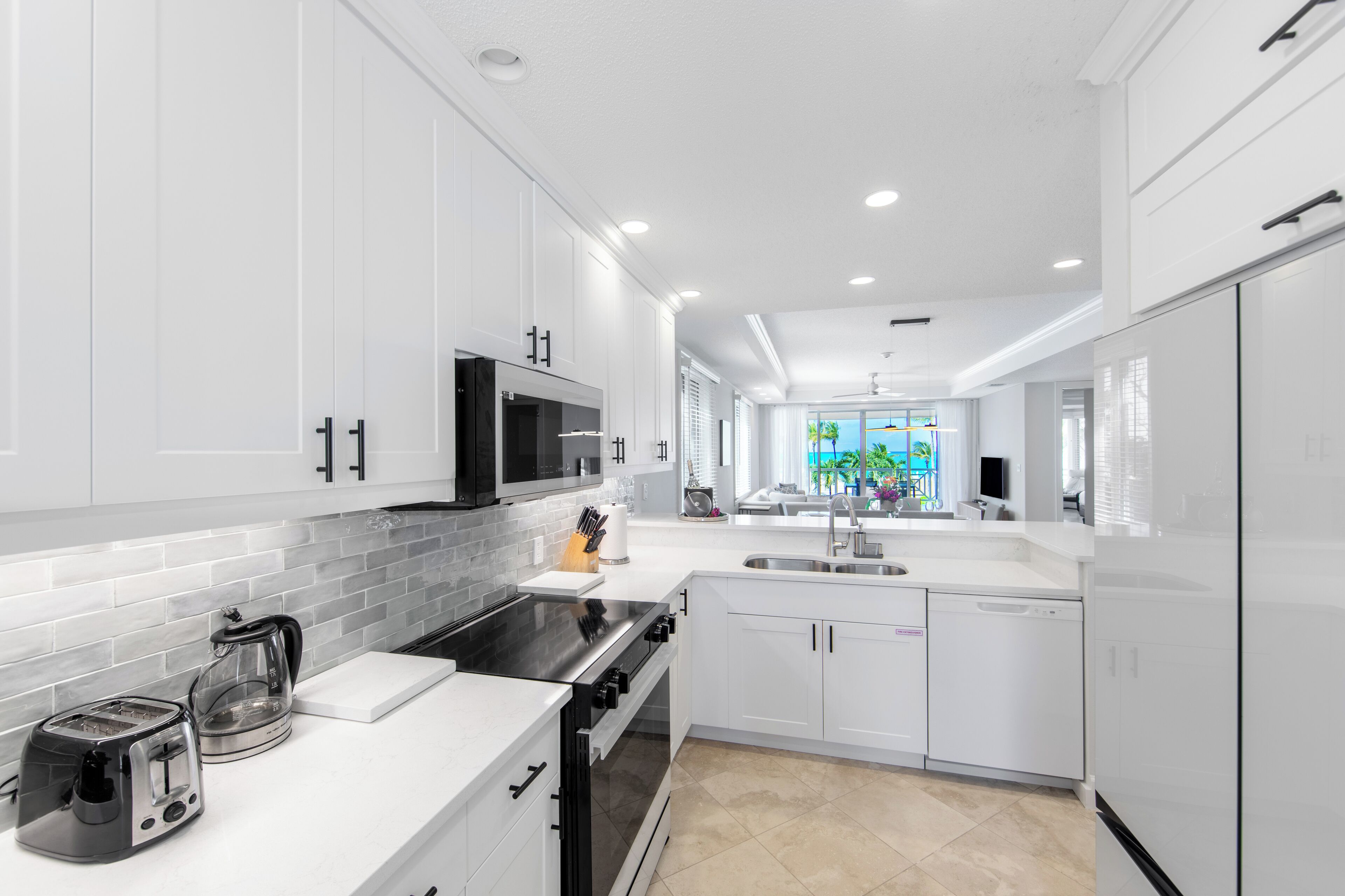 Une cuisine moderne avec des meubles blancs, une cuisinière noire et un four à micro-ondes.