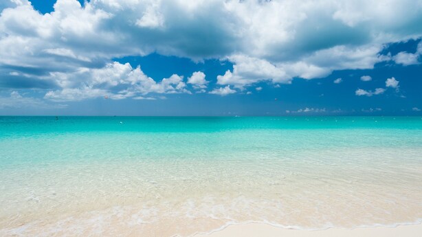 A beach with clear turquoise water and white sand.