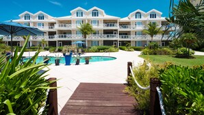 A resort with a pool, multiple balconies, and lush landscaping.