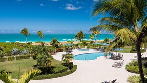 A resort with a pool, beach, and palm trees.