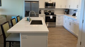 Een moderne keuken met witte kastjes, roestvrijstalen apparatuur en een centraal eiland met een spoelbak.