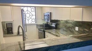 Una cocina moderna con encimera de mármol, electrodomésticos de acero inoxidable y armarios blancos.