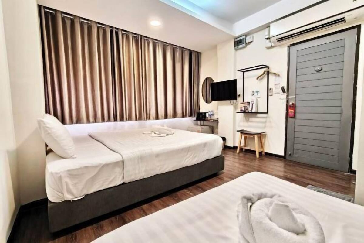 A hotel room with a bed, a desk, a chair, a television, and a door.