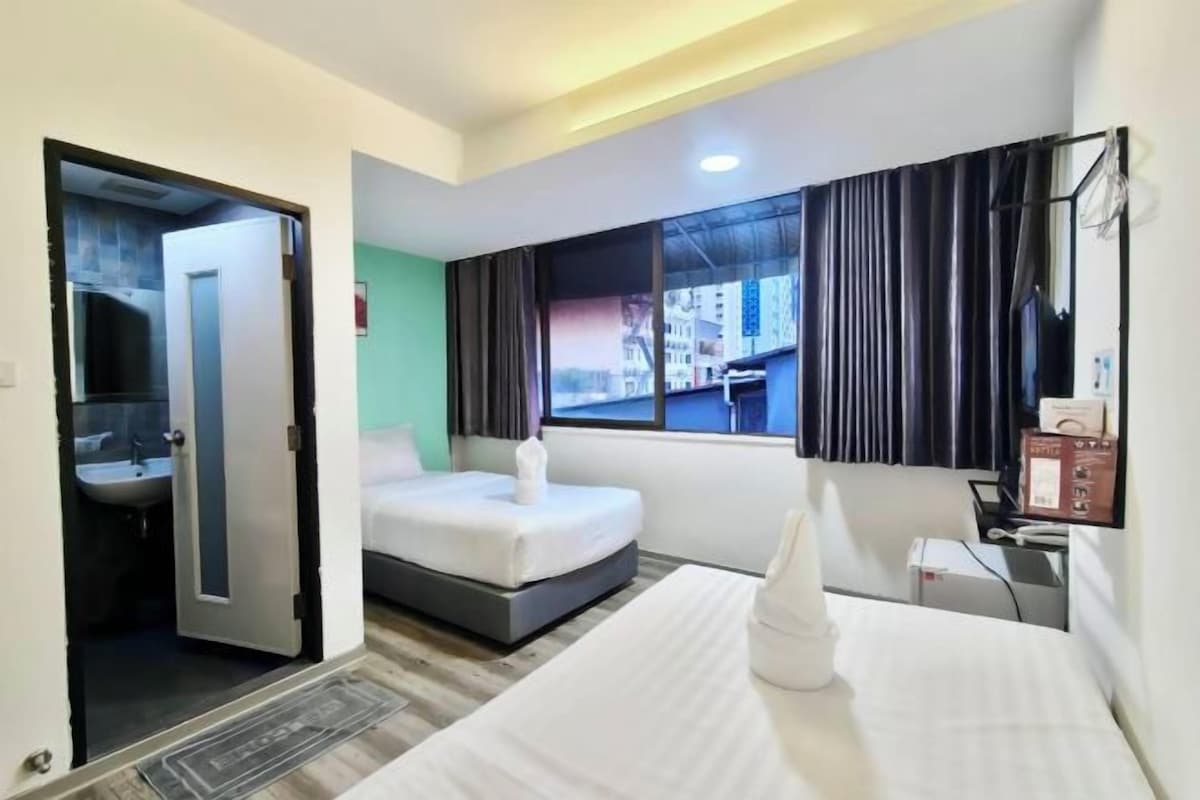 A hotel room with a bed, a bathroom, a window with curtains, and a desk with a mirror.