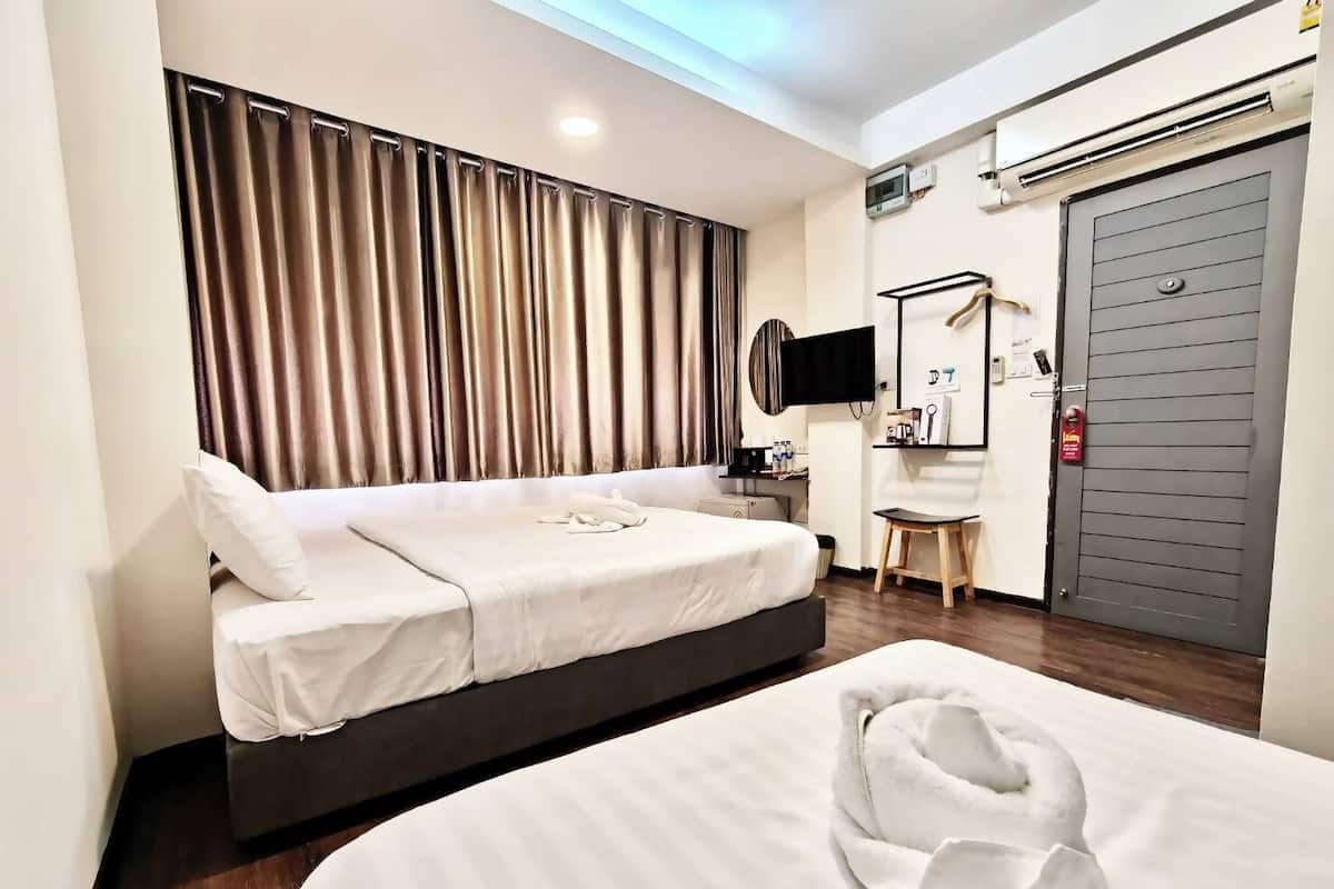 A hotel room with two beds, a TV, a desk, and a wardrobe.