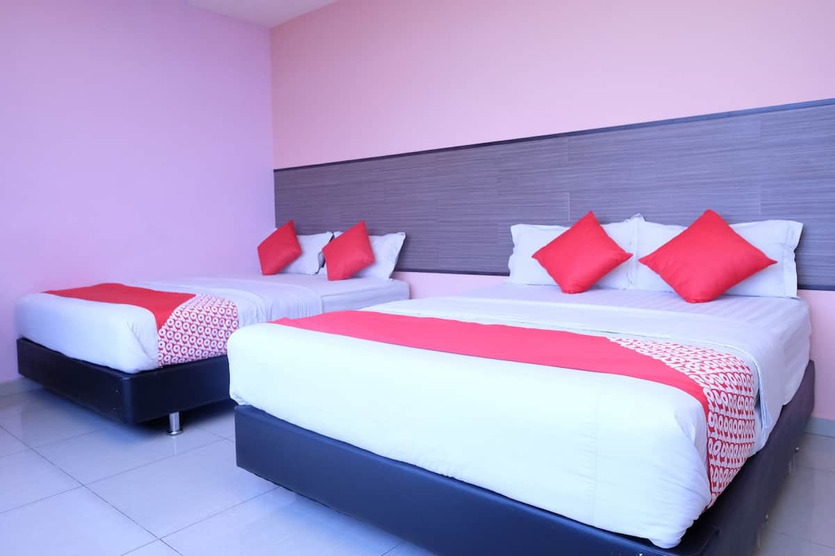 Habitación de hotel con dos camas, cada una con ropa blanca y almohadas rojas. La habitación presenta un diseño moderno con cabecera gris y paredes rosadas.