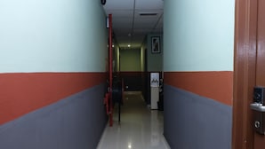 Un pasillo con paredes rojas y grises, piso de baldosas y un dispensador de agua.