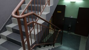 Una escalera con barandilla marrón y escalones grises y blancos.