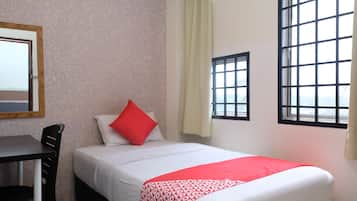 Une chambre d’hôtel avec un lit, un bureau et deux fenêtres.