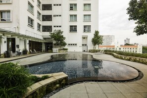 A modern building with a swimming pool, outdoor seating, and a view of the city skyline.