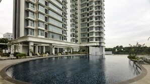 A modern hotel with a large swimming pool, a covered outdoor area with seating, and a tall building in the background. - OYO Home 524 Elegant  2 BR Dua Sentral (Kuala Lumpur)