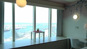 A room with large windows offering a view of a city and water. There's a small table with a plant on it. - 85 Eagle Hotel (Kaohsiung)