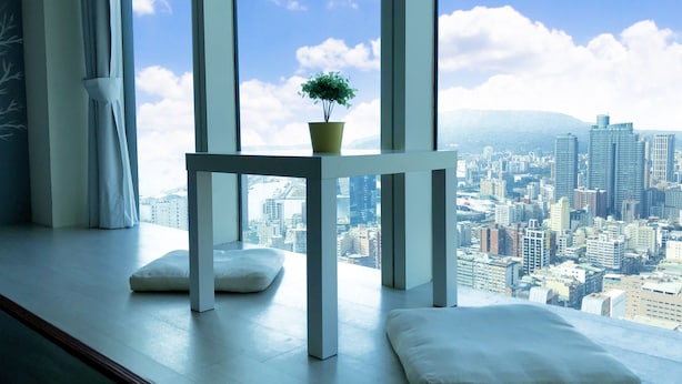 A modern room with a city view, a white table with a plant, and two white cushions. - 85 Eagle Hotel (Kaohsiung)