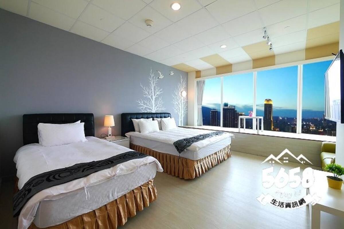 A hotel room with two beds, a large window with a city view, and a modern design.
