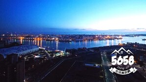 A nighttime cityscape with a waterfront, illuminated buildings, and a logo with the number 5658. - 85 Eagle Hotel (Kaohsiung)