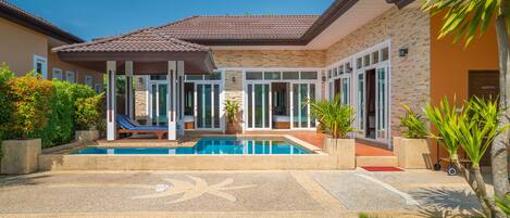 A house with a swimming pool, covered patio, and a small garden area.