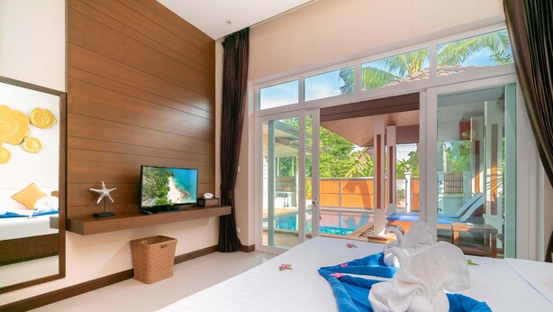 Habitación de hotel con cama, televisión, ventana con vista a una piscina y zona exterior, y pared de madera.