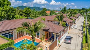 Una hilera de casas con tejados de tejas, una piscina y una calle con coches.