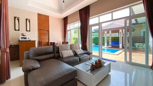 Una sala de estar moderna con un sofá grande, una mesa de centro y vista a una piscina.
