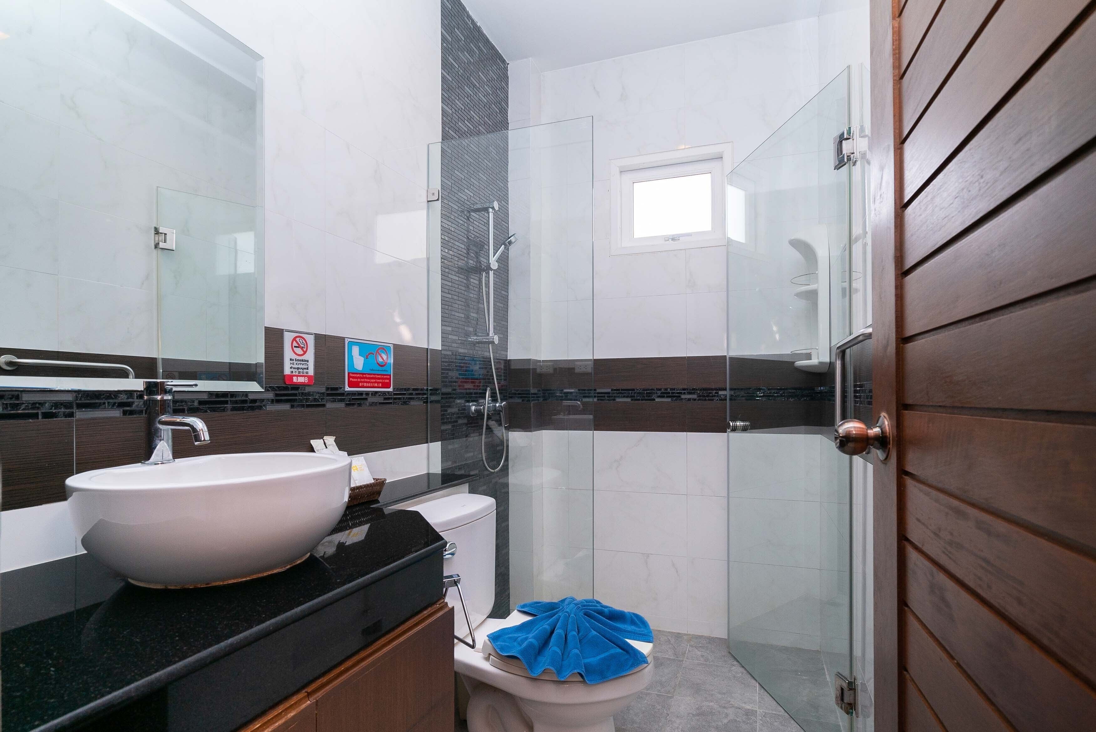 Un baño moderno con un lavabo grande de color blanco, una cabina de ducha de cristal y una puerta de madera.