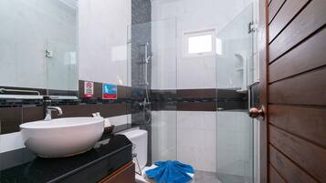 Un baño moderno con un lavabo grande de color blanco, una cabina de ducha de cristal y una puerta de madera.