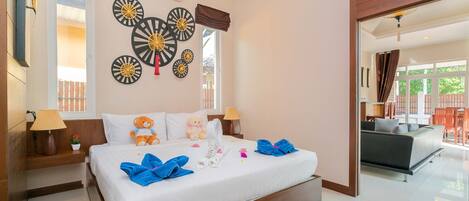 A hotel room with a large bed, bedside tables, a wall clock, and a view of the outdoor seating area.