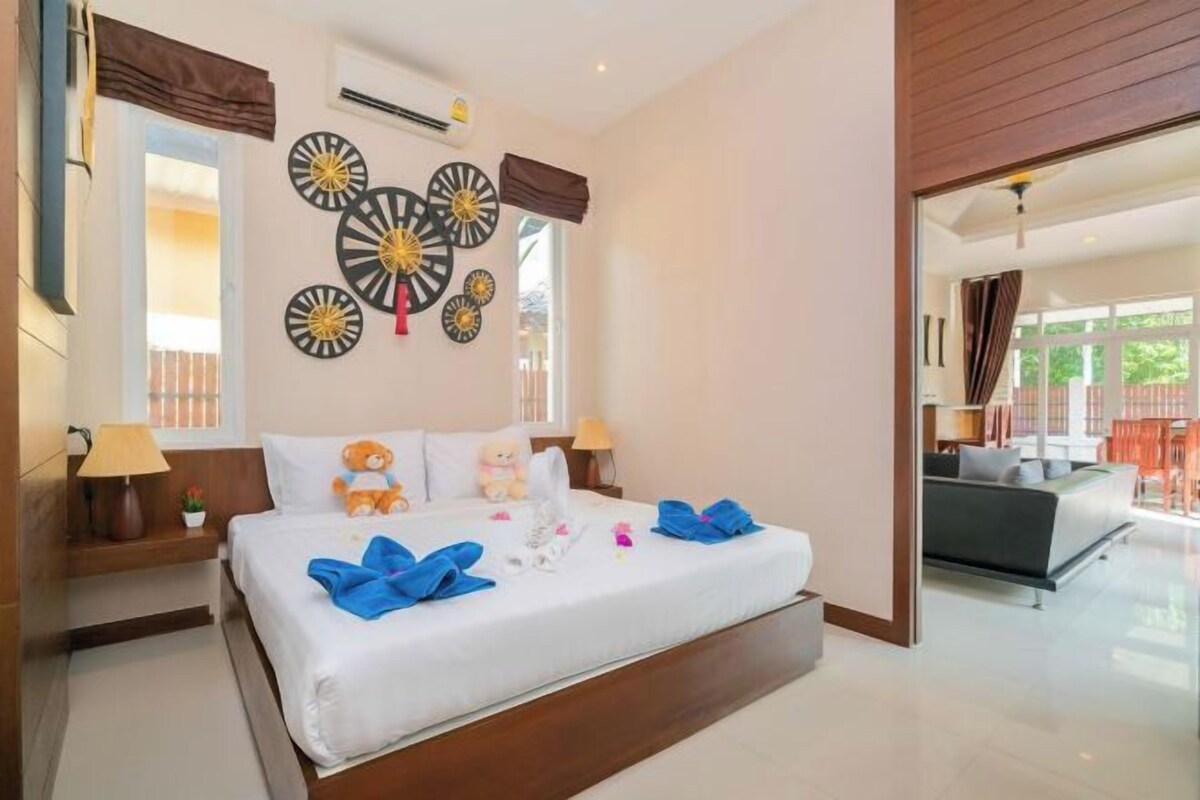 A hotel room with a large bed, bedside lamps, decorative wall art, and a view of the outdoor area.