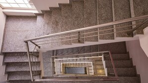 Escadaria de pedra com vários níveis, corrimãos de metal e um claraboia acima.