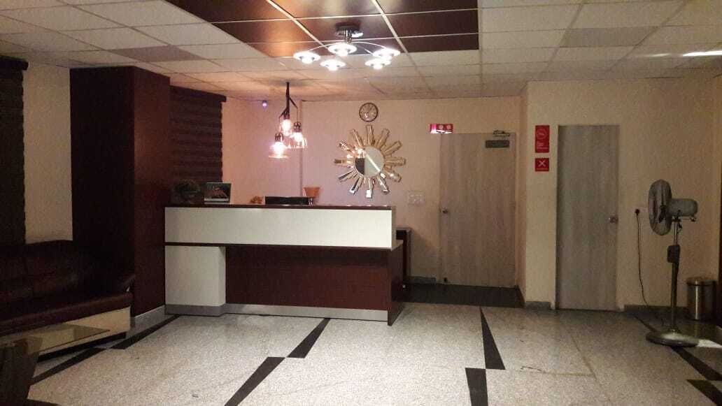 Zona de recepción con mostrador, un reloj y una puerta.