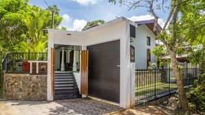Une maison moderne avec une porte de garage, un escalier menant à l’entrée et un mur en pierre.