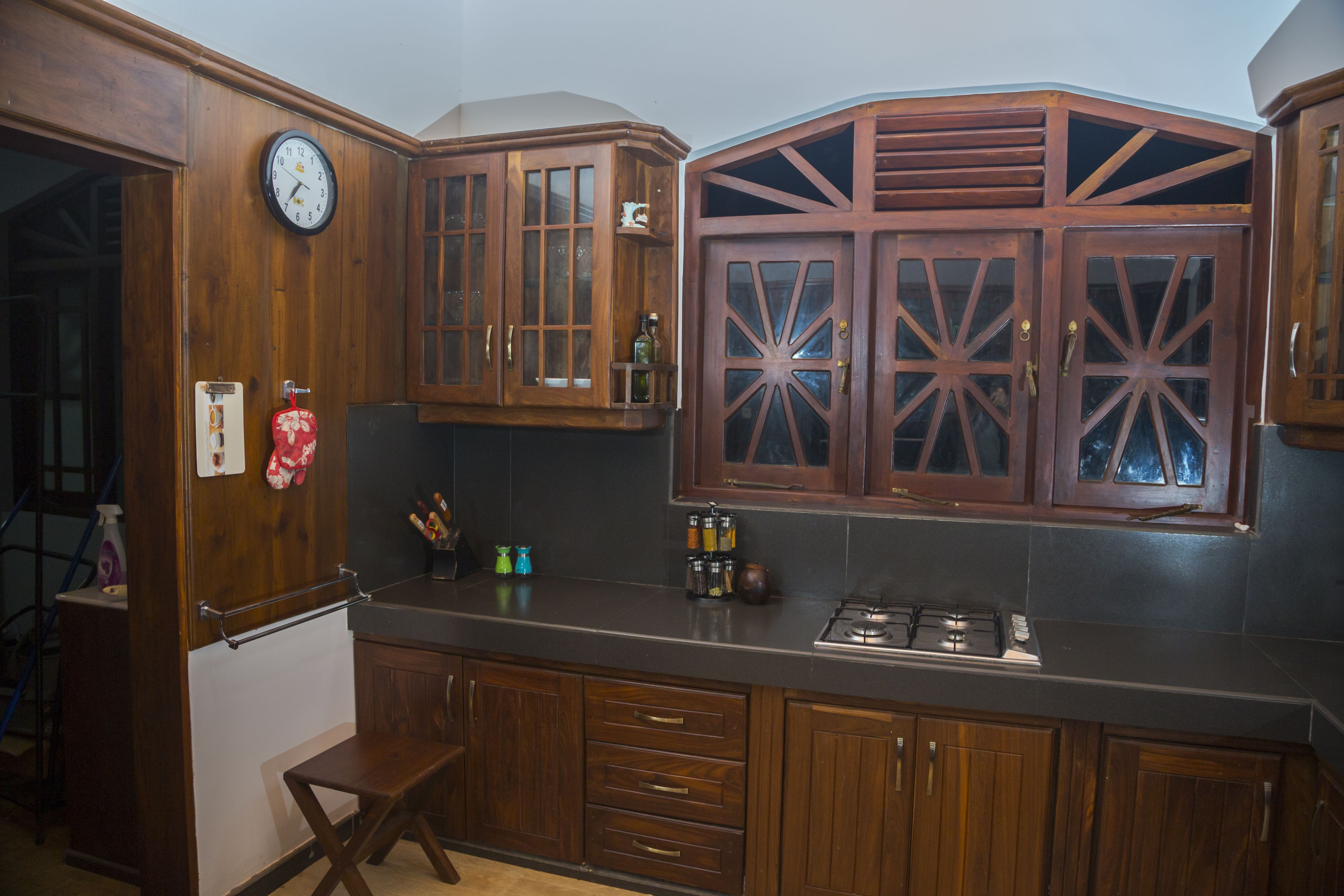 A kitchen with wooden cabinets, a clock, and a stove.