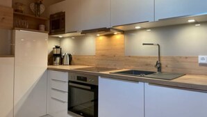 A modern kitchen with white cabinetry, a stainless steel sink, and a built-in oven.