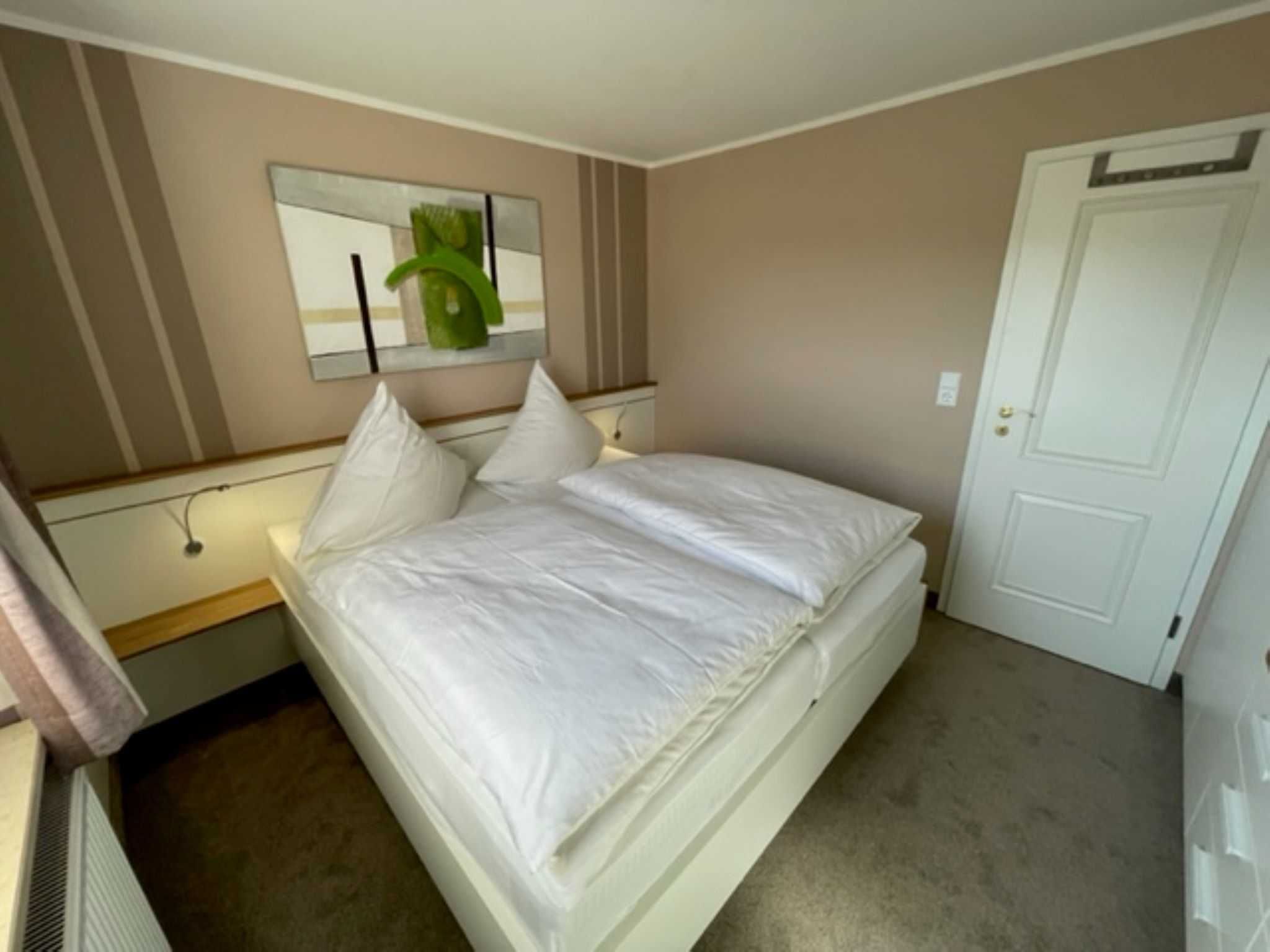 Een slaapkamer met een bed, een spiegel en een deur.