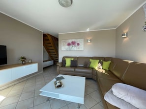 A modern living room with a brown sofa, white coffee table, and a TV on a wooden cabinet.