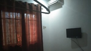 A room with a bed, an air conditioning unit, a television mounted on the wall, and a curtain. - Tengoz Lodge (Morogoro)